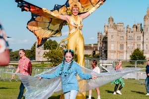 Guests with butterfly stilt walkers at Classic Ibiza Burghley 2023