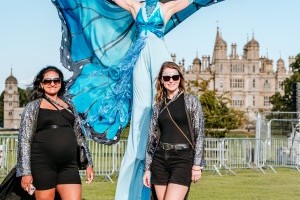 Guests with butterfly stilt walkers at Classic Ibiza Burghley 2023
