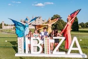 Guests with butterfly stilt walkers at Classic Ibiza Burghley 2023