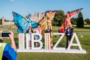 Guests with butterfly stilt walkers at Classic Ibiza Burghley 2023